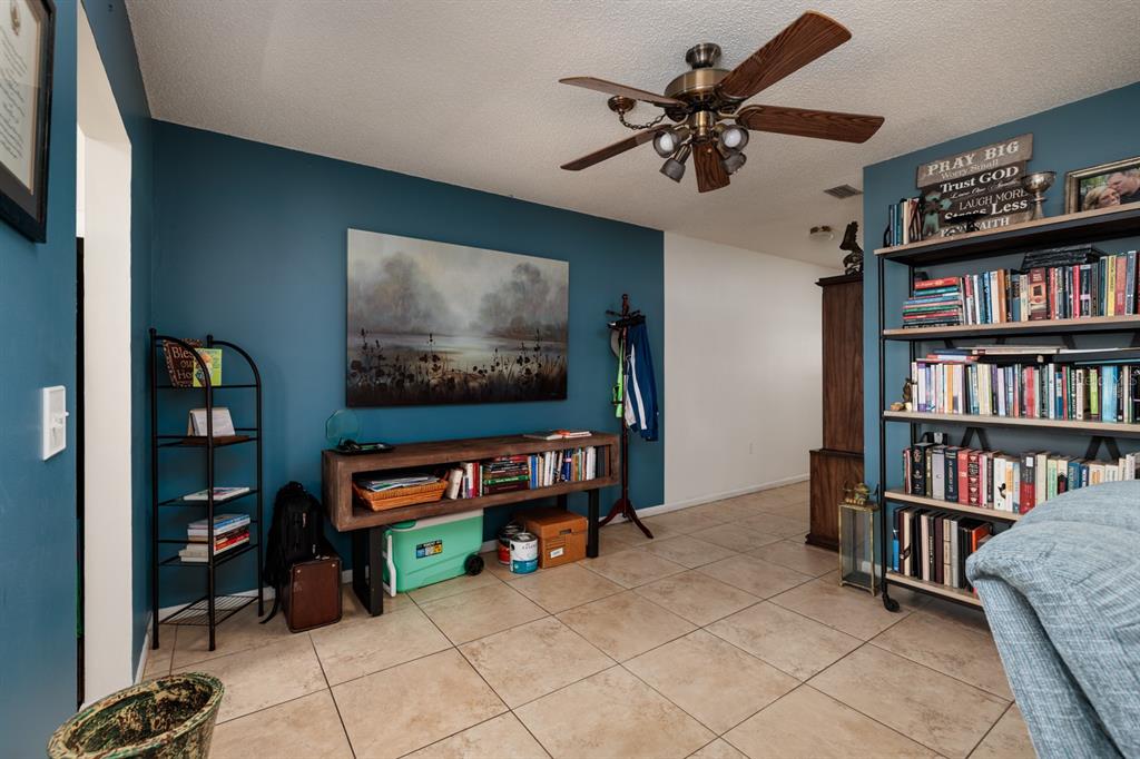 A room with blue walls, tile flooring, a ceiling fan, and two bookshelves — 5623 80TH STREET N UNIT 504, ST PETERSBURG, FL