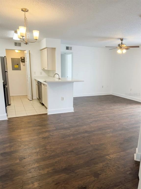 An open-concept kitchen and living area features dark wood-look flooring and white cabinetry — 1218 BERMUDA LAKES LANE UNIT 203, KISSIMMEE, FL