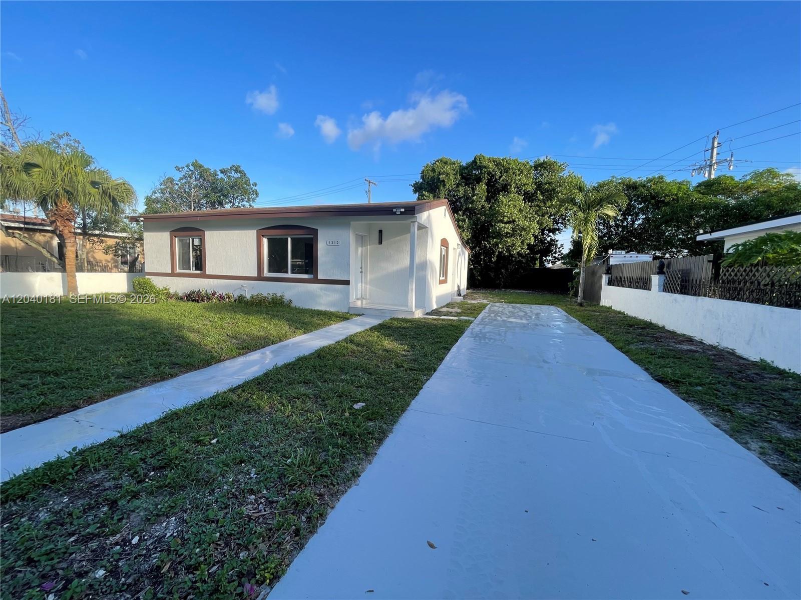 A single-story house with a white exterior, a paved driveway, and a small front yard — 1310 Sharazad Blvd, Opa-Locka FL 33054, OPA-LOCKA, FL