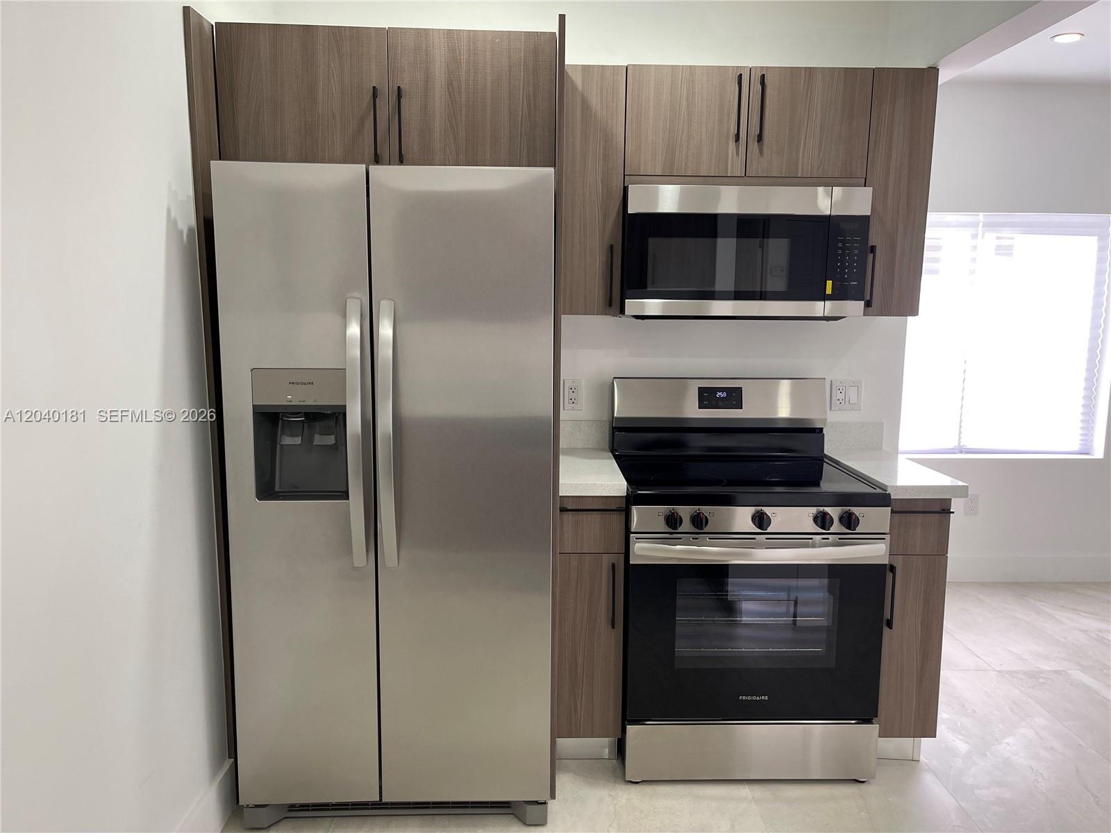 A kitchen features stainless steel appliances, wood-grain cabinets, and light-colored countertops — 1310 Sharazad Blvd, Opa-Locka FL 33054, OPA-LOCKA, FL