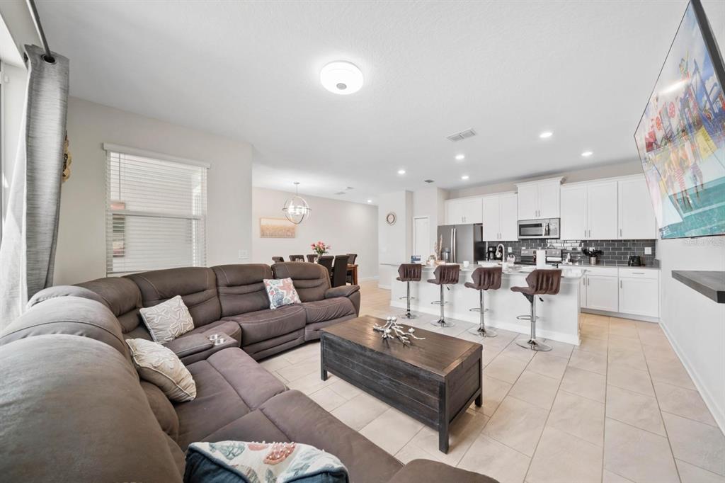 An open-concept living room and kitchen feature a large sectional sofa and breakfast bar seating — 900 PEBBLE BEACH DRIVE, DAVENPORT, FL