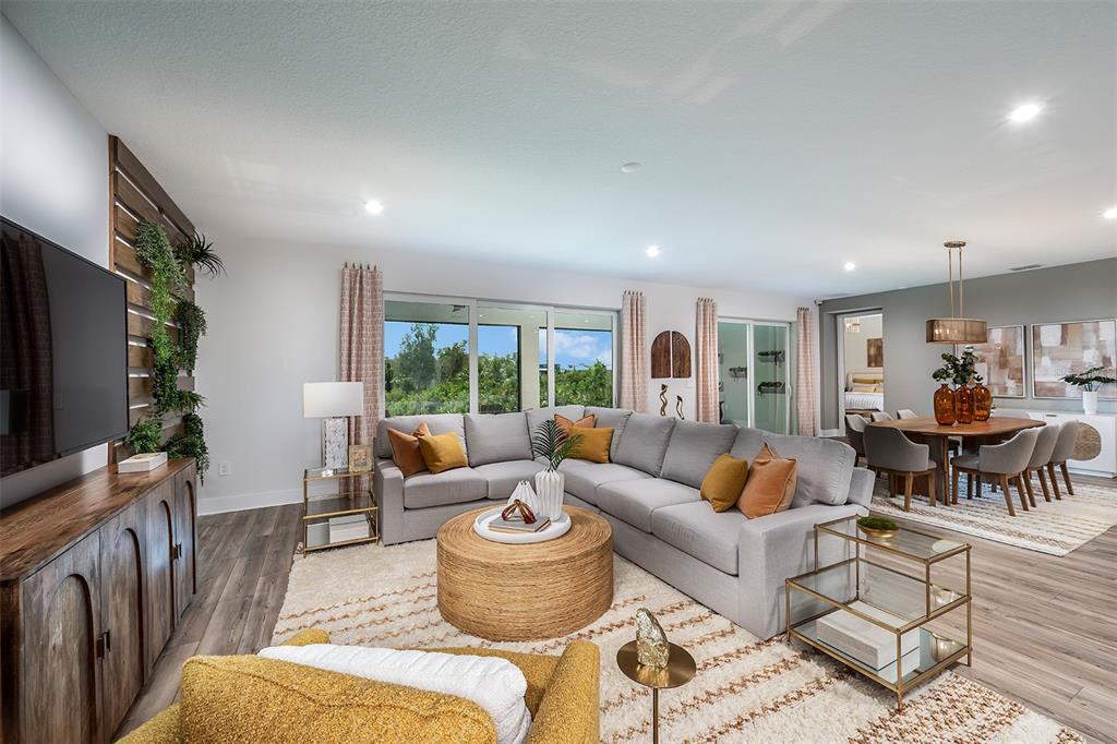A living room features a large gray sectional, a round woven coffee table, and wood flooring — 12012 ETHOS COURT, VENICE, FL