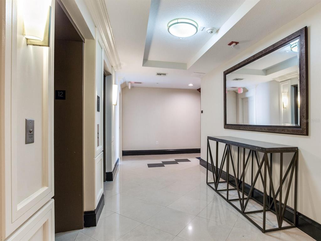 A hallway features a tiled floor, an elevator, a console table, and a large wall mirror — 3507 BAYSHORE BOULEVARD UNIT 1202, TAMPA, FL