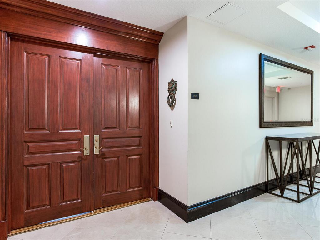 A pair of dark wood double doors stands next to a wall with a mirror — 3507 BAYSHORE BOULEVARD UNIT 1202, TAMPA, FL