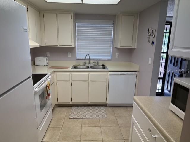 A kitchen features white cabinets, light countertops, a double sink, and a white dishwasher — 1100 EAST BAY DRIVE UNIT 89, LARGO, FL