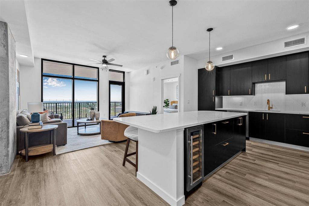 A modern kitchen with dark cabinets and a white island overlooks a living area — 221 MAIN STREET N UNIT B1-1013, ST PETERSBURG, FL