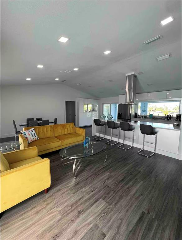 An open-concept living area features a yellow sofa, a kitchen island, and dark wood flooring — 3004 BANYAN WAY, PUNTA GORDA, FL