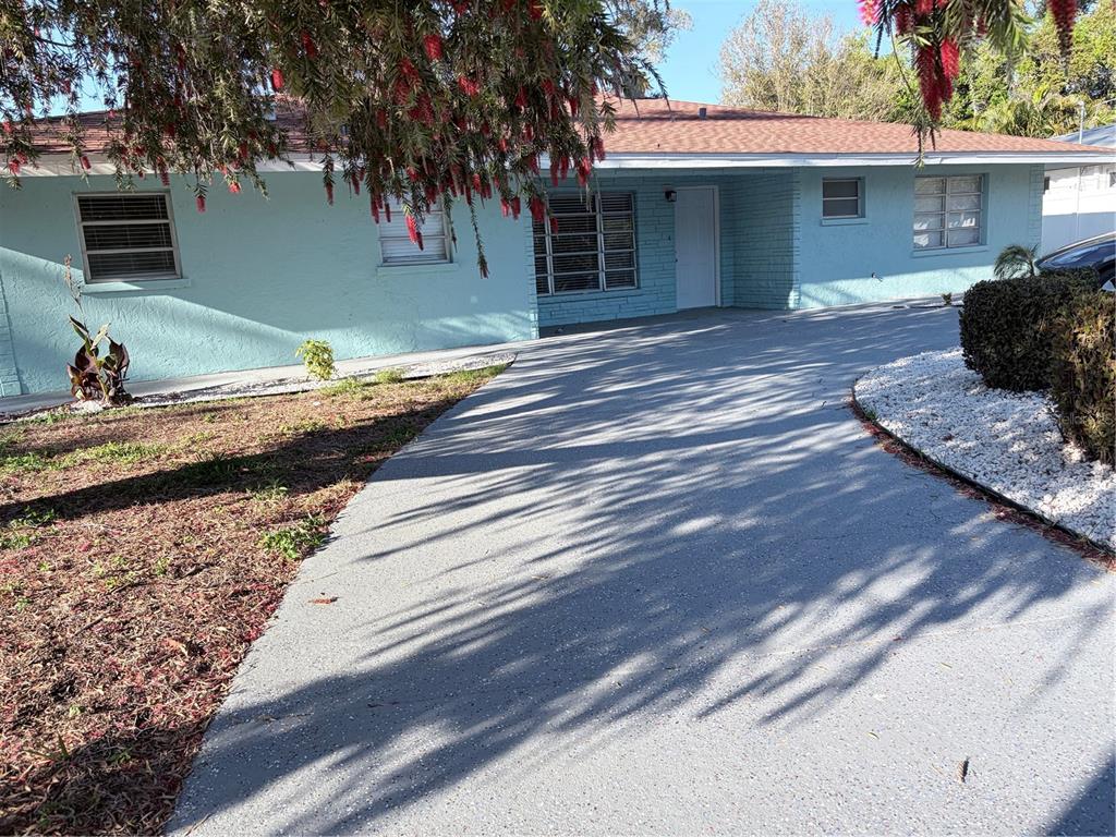 A light blue single-story house features a paved driveway and a large overhanging tree — 1339 22ND STREET, SARASOTA, FL