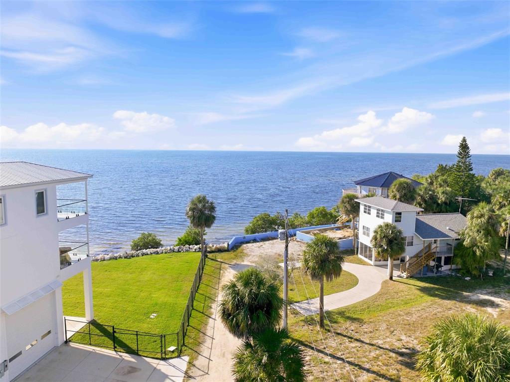 An aerial view shows two coastal houses with a grassy yard and oceanfront access — 3461 CYCLONE DRIVE, WEEKI WACHEE, FL