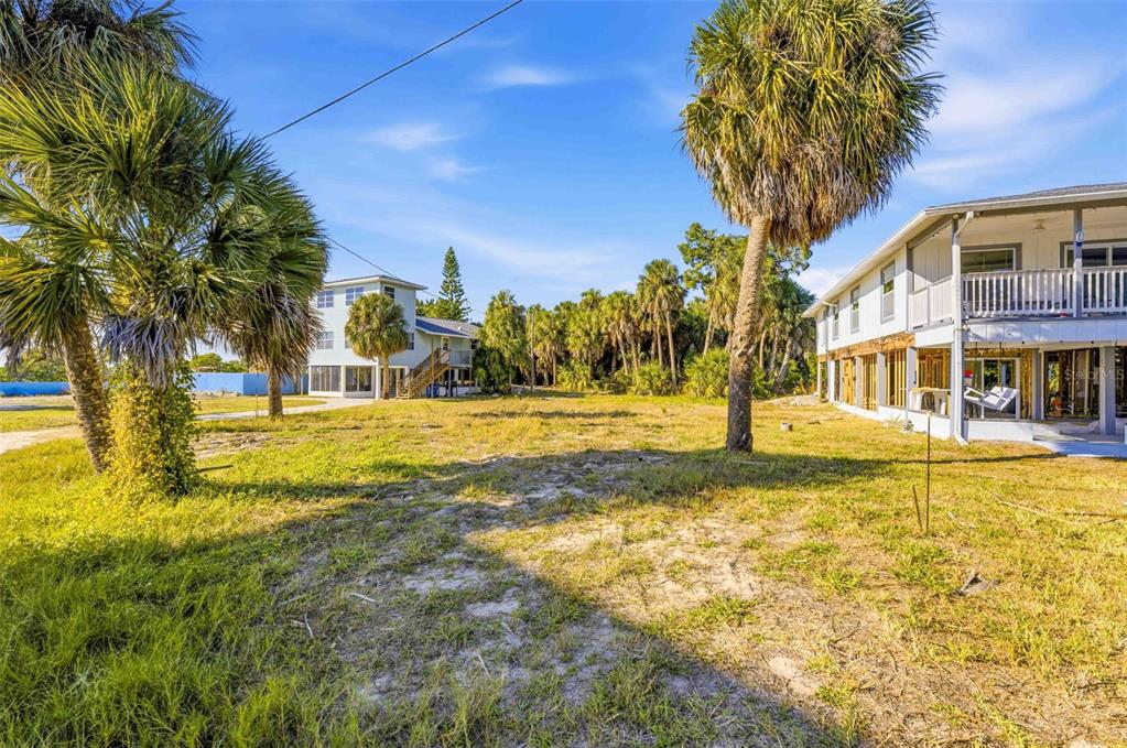 A grassy lot sits between two multi-story houses surrounded by palm trees under a blue sky — 3461 CYCLONE DRIVE, WEEKI WACHEE, FL