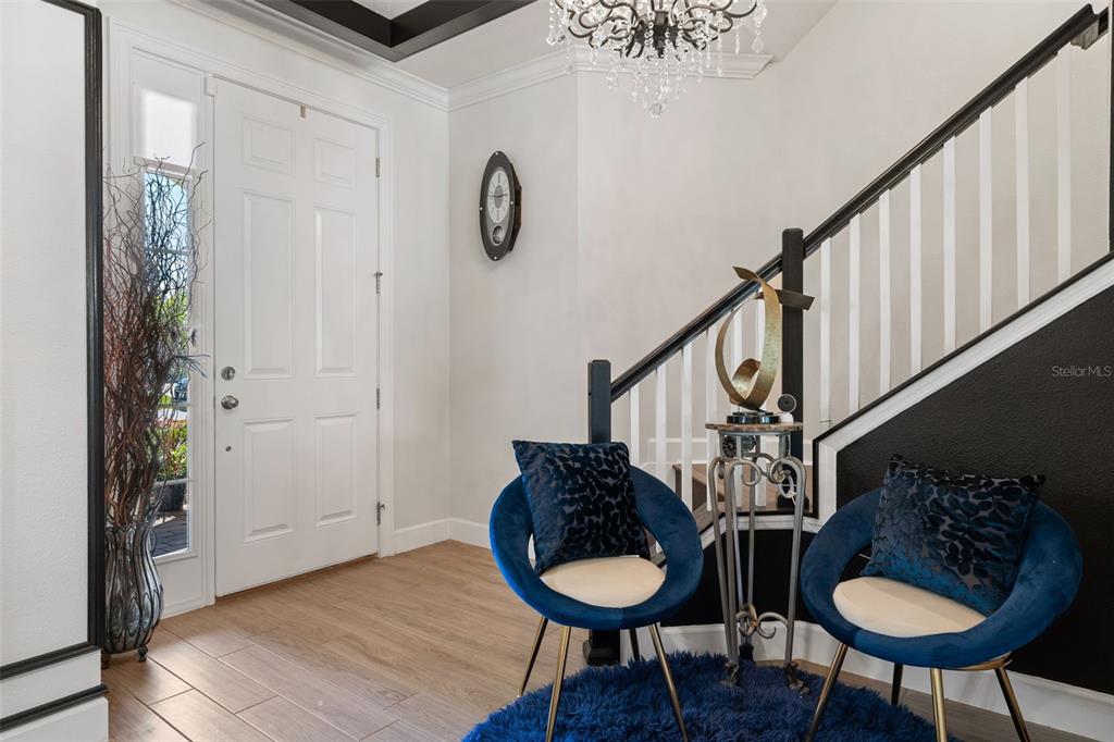 An entryway features a white door, a staircase with black railings, and two blue chairs — 2534 CEDAR SHAKE COURT, OVIEDO, FL