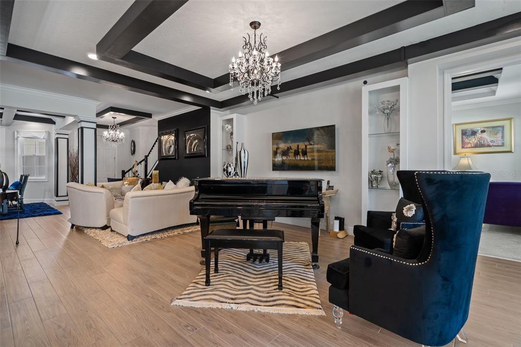 A living room features a black grand piano, dark ceiling beams, and a crystal chandelier — 2534 CEDAR SHAKE COURT, OVIEDO, FL