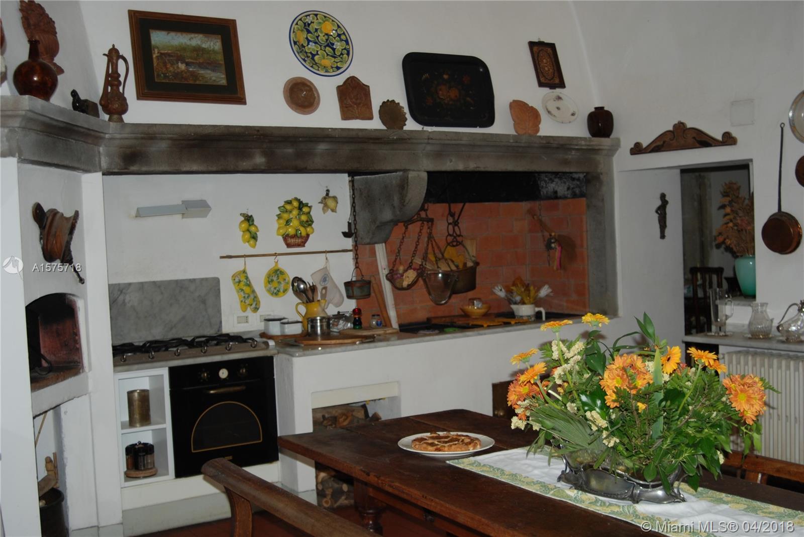 A rustic kitchen features a large stone fireplace, a wooden table, and decorative wall items — 0 UNITA IMMOBILIARE IN, FL 0, FL