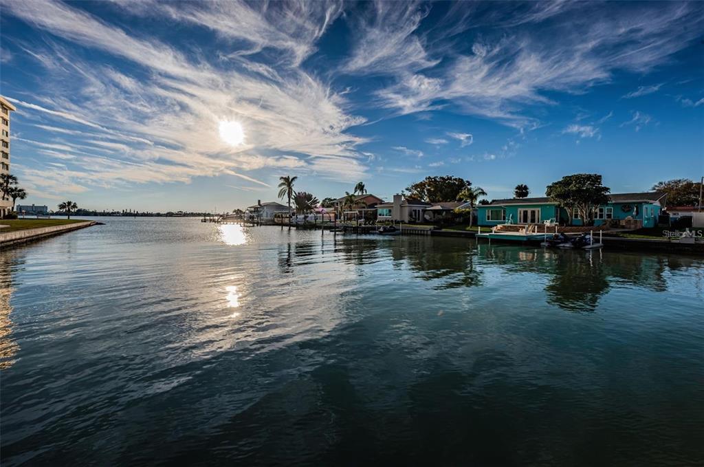 A view of a canal with waterfront houses, docks, and a bright, cloudy sky — 4725 COVE CIRCLE UNIT 210, ST PETERSBURG, FL