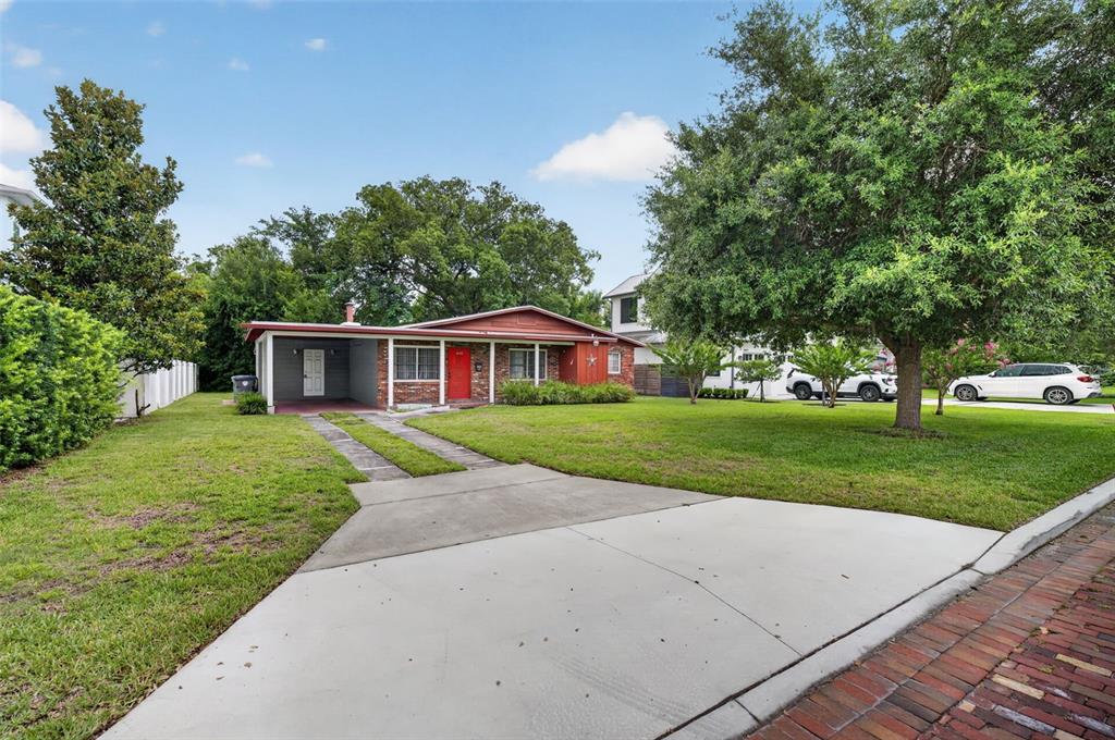 A single-story brick house with a red door and attached carport sits on a lawn — 1622 ARBOR PARK DRIVE, WINTER PARK, FL