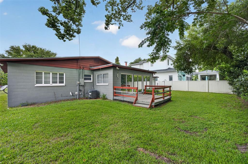 A gray concrete block house features a wooden deck and a large grassy backyard — 1622 ARBOR PARK DRIVE, WINTER PARK, FL