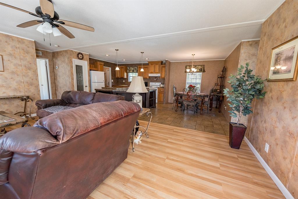 An open-concept living room and kitchen featuring wood-look flooring, brown walls, and wooden cabinets — 21800 SW 15TH AVENUE, NEWBERRY, FL