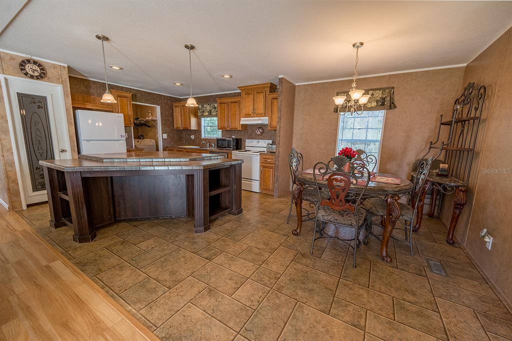 A kitchen and dining area with tile flooring, wooden cabinets, and a central island — 21800 SW 15TH AVENUE, NEWBERRY, FL