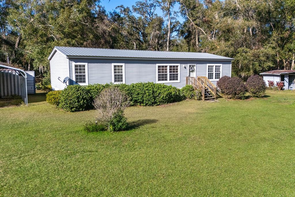 A light gray manufactured home with a metal roof sits on a grassy lot — 21800 SW 15TH AVENUE, NEWBERRY, FL
