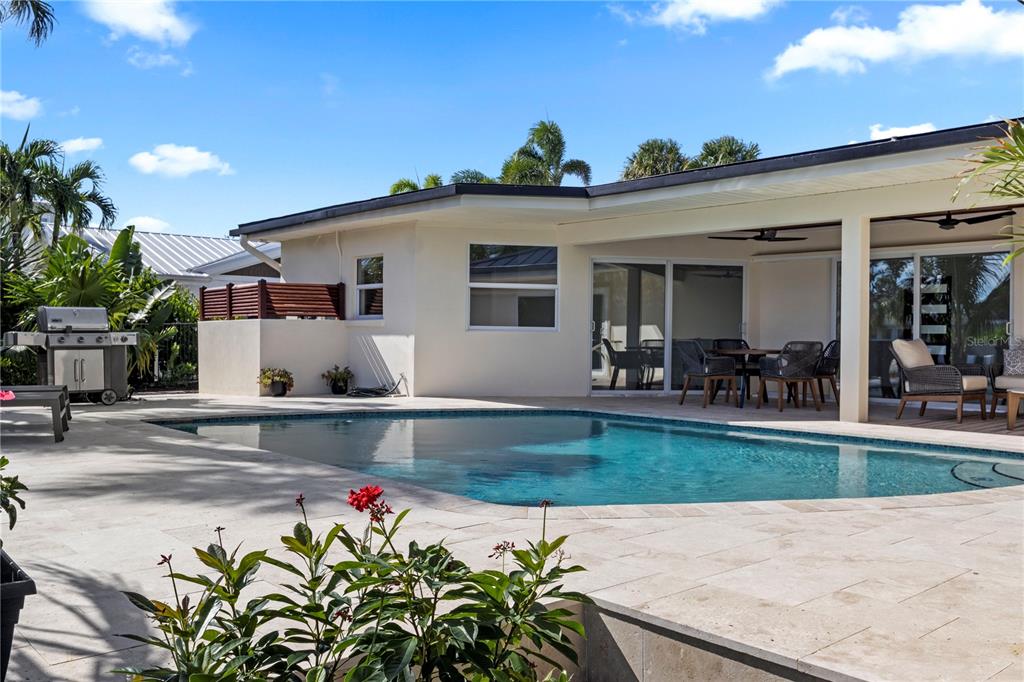 A backyard patio features a swimming pool, outdoor dining area, and a stainless steel grill — 624 DUNDEE LANE, BRADENTON BEACH, FL