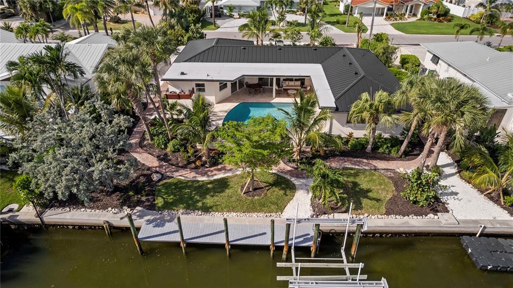 An aerial view shows a house with a dark metal roof, pool, and private boat dock — 624 DUNDEE LANE, BRADENTON BEACH, FL