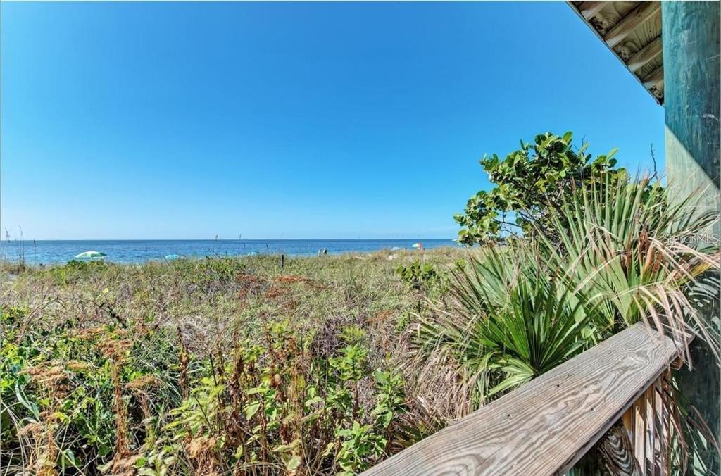 A wooden deck railing overlooks a grassy dune area leading to the ocean — 12 PETUNIA COURT, PLACIDA, FL