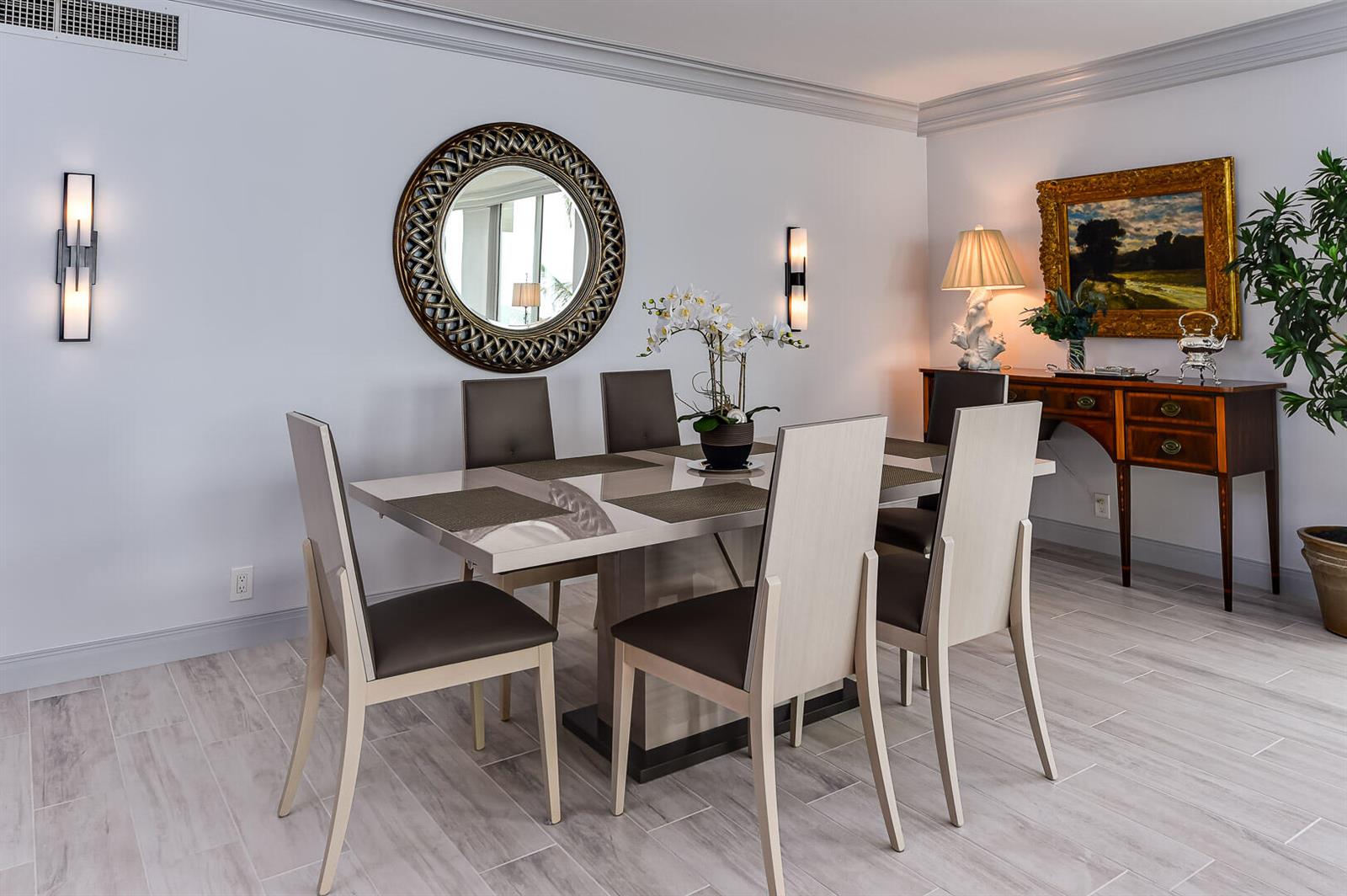 A dining room features a modern table with six chairs, a round mirror, and wall sconces — 340 S Ocean Boulevard # 2b, Palm Beach FL 33480, PALM BEACH, FL