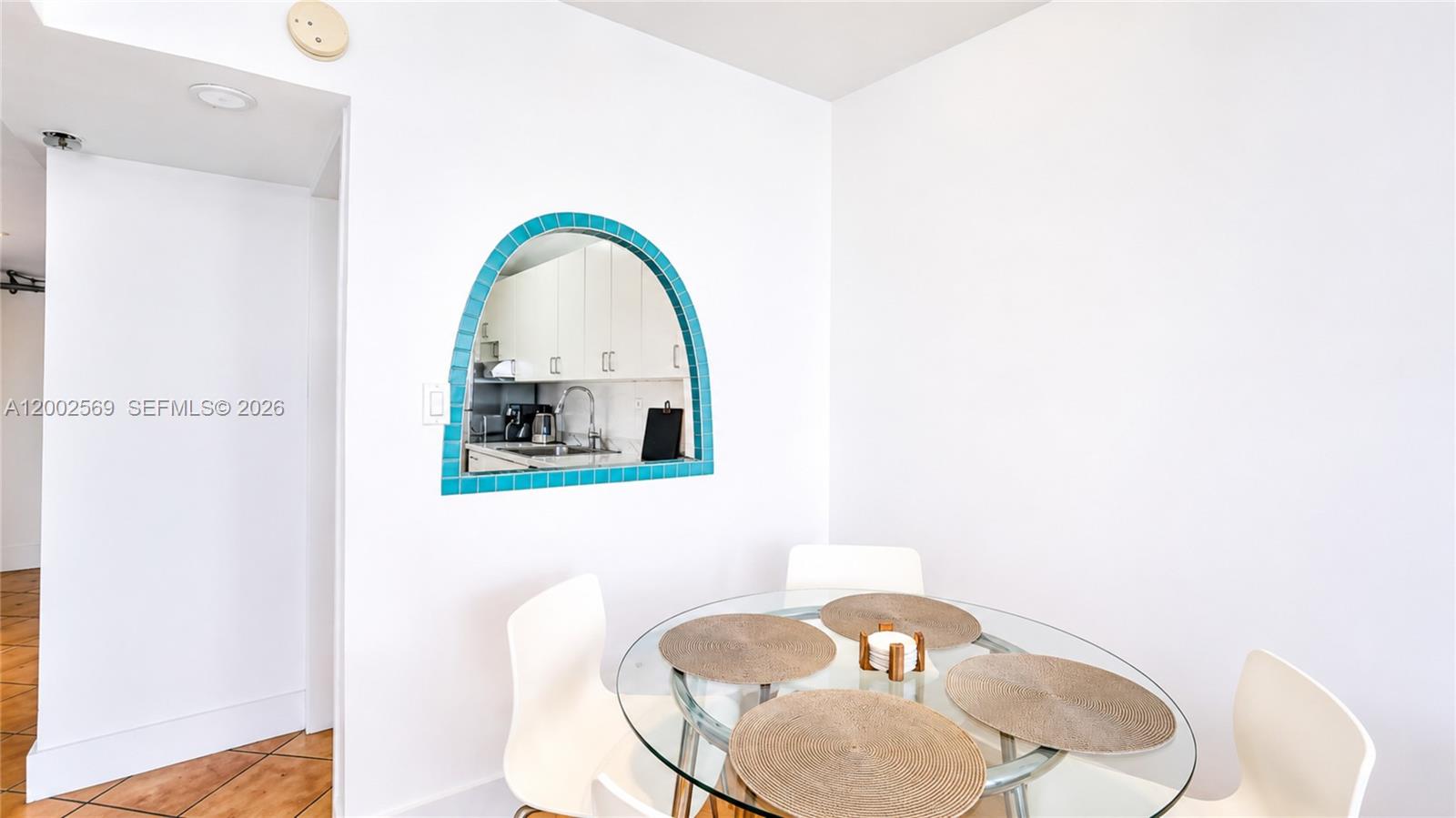 A dining area features a glass table and an arched pass-through window with blue tiles — 100 Lincoln Rd # 1209, Miami Beach FL 33139, MIAMI BEACH, FL