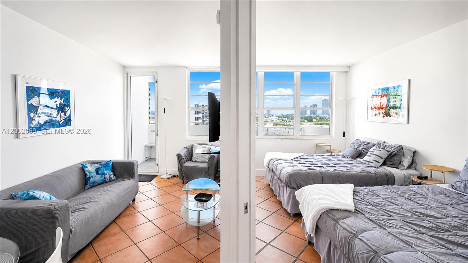 A living area with a sofa and a bedroom with two beds share a space — 100 Lincoln Rd # 1209, Miami Beach FL 33139, MIAMI BEACH, FL