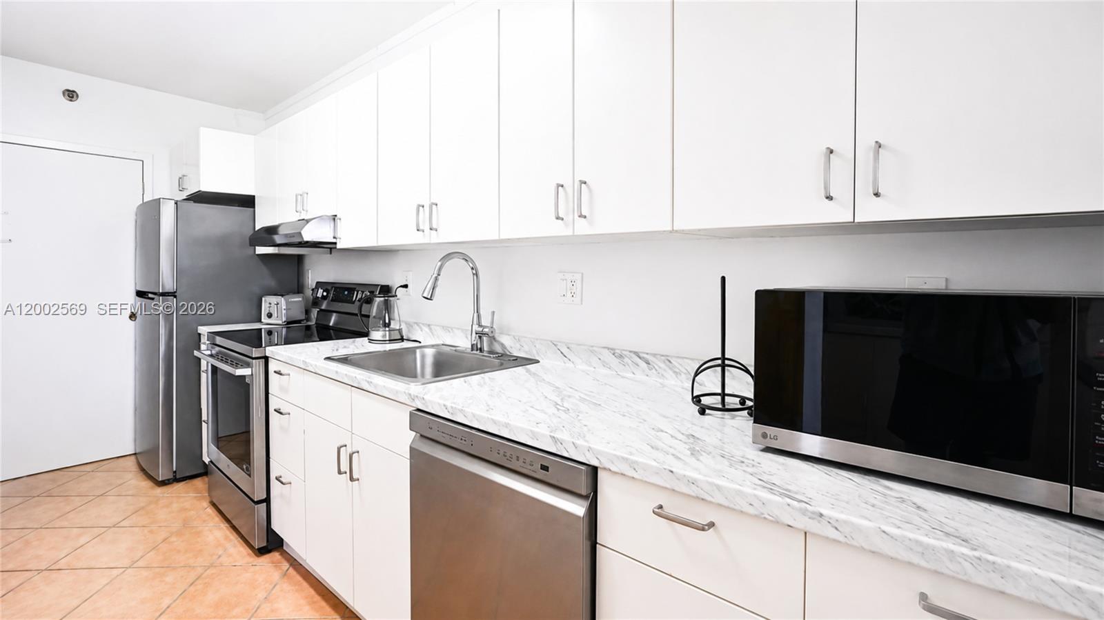 A kitchen features white cabinets, stainless steel appliances, and a marble-patterned countertop — 100 Lincoln Rd # 1209, Miami Beach FL 33139, MIAMI BEACH, FL