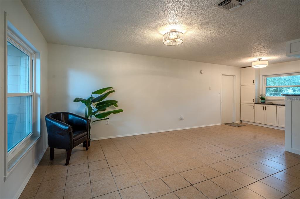 A room with beige tile flooring, a dark leather chair, a potted plant, and white cabinets — 1049 BIRCH BOULEVARD, TAVARES, FL