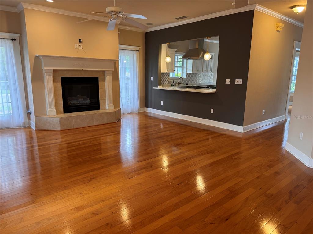 A living room with hardwood floors, a fireplace, and an open pass-through to the kitchen — 5020 NW 10TH PLACE, GAINESVILLE, FL