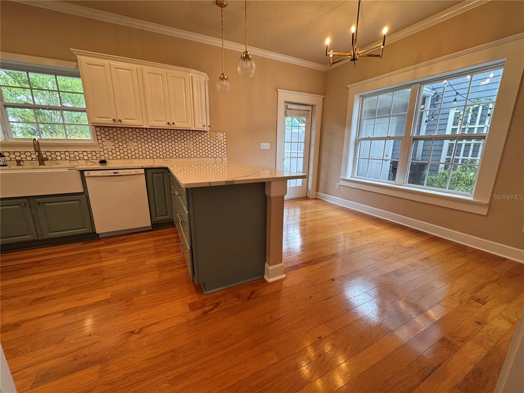 A kitchen features white upper cabinets, green lower cabinets, a marble island, and hardwood floors — 5020 NW 10TH PLACE, GAINESVILLE, FL