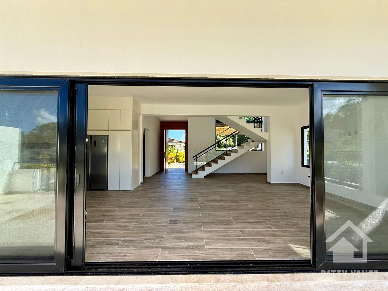 An open-plan living area features wood-look tile floors, a modern staircase, and a stainless refrigerator — Perla Marina Residential Calle Perla, FL