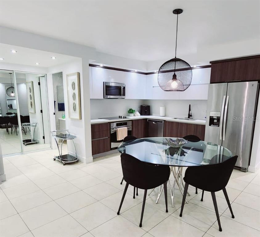 A modern kitchen features dark wood lower cabinets, white upper cabinets, and a glass dining table — Gallery Plaza DE DIEGO AVE. UNIT 1102-S, SAN JUAN, PR