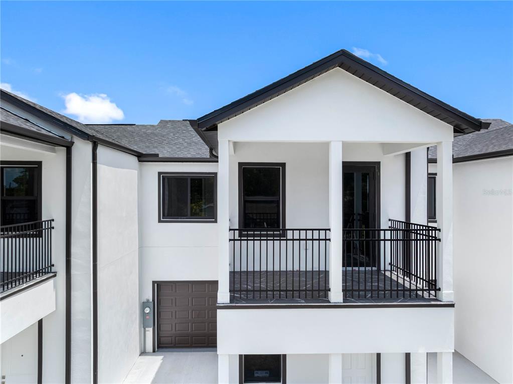 The exterior of a modern two-story white house features a balcony with black metal railings — 7015 N CENTRAL AVENUE Unit B, TAMPA, FL