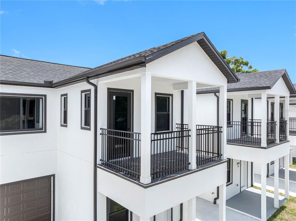 An exterior view of a white two-story building featuring a balcony with black metal railings — 7015 N CENTRAL AVENUE Unit B, TAMPA, FL