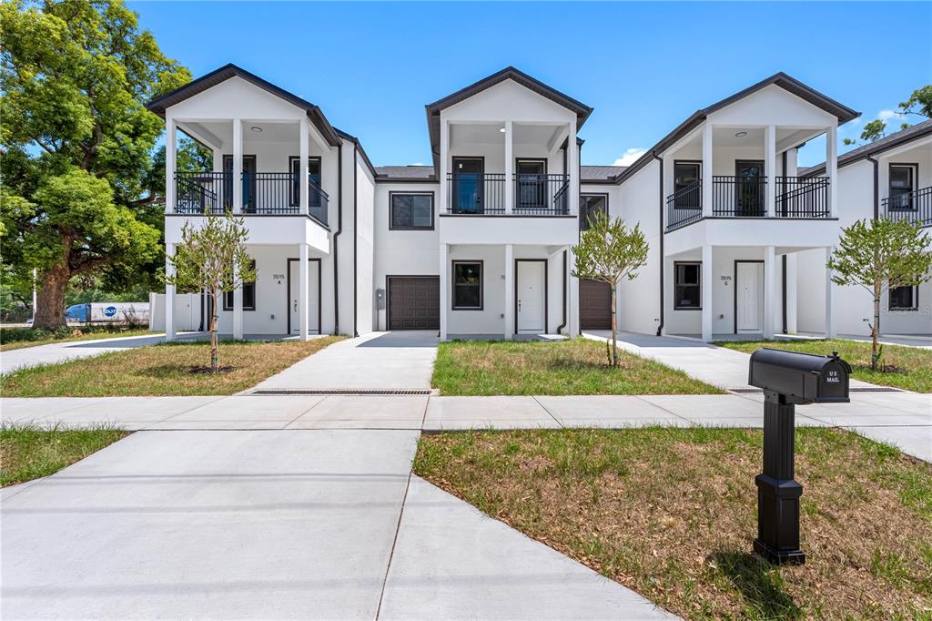 A row of modern white townhouses with balconies, garages, and concrete driveways under a blue sky — 7015 N CENTRAL AVENUE Unit B, TAMPA, FL