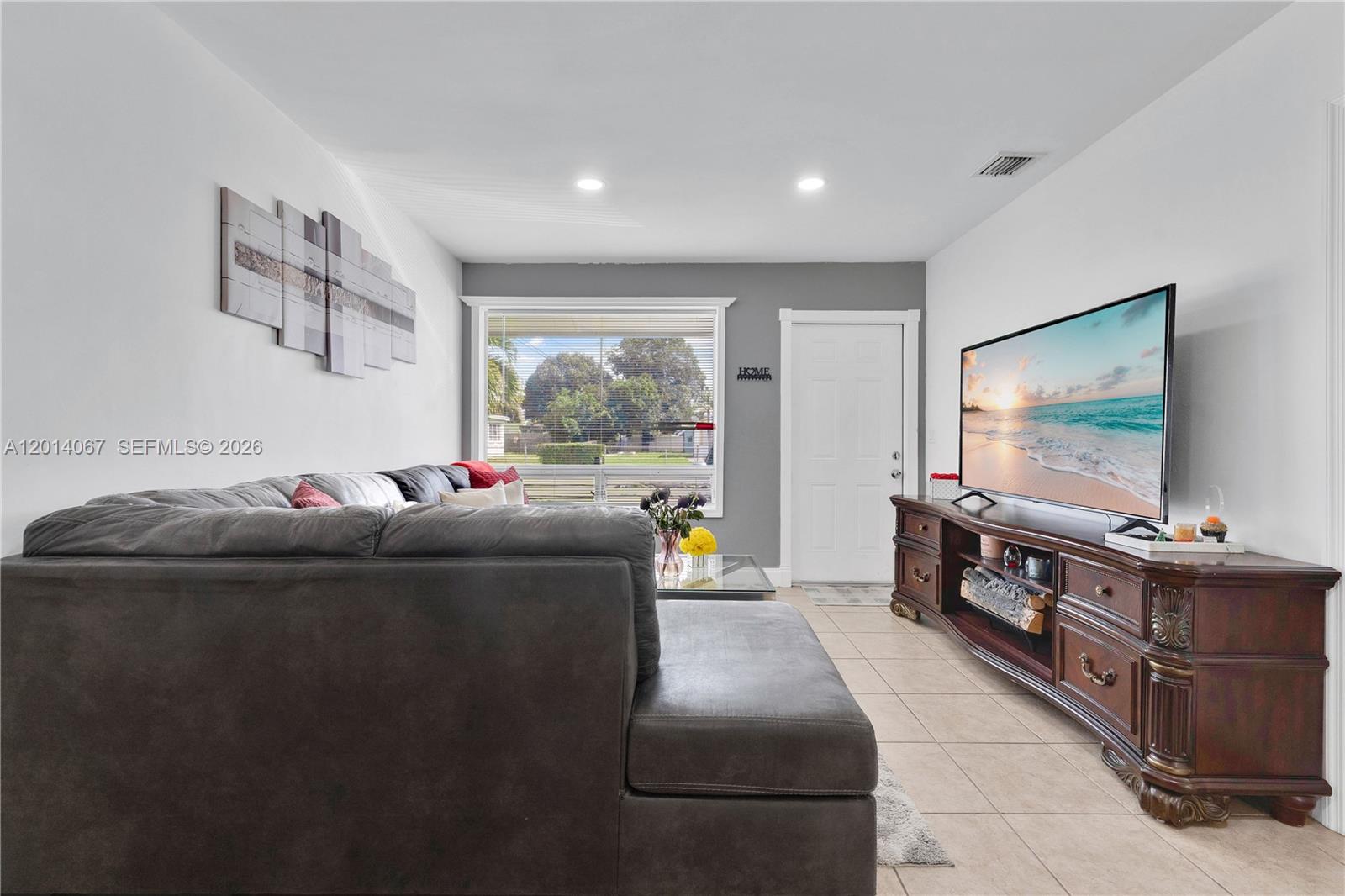 A living room features a dark sectional sofa, a large television on a wooden console, and tile flooring — 3171 NW 16th St, Lauderhill FL 33311, LAUDERHILL, FL