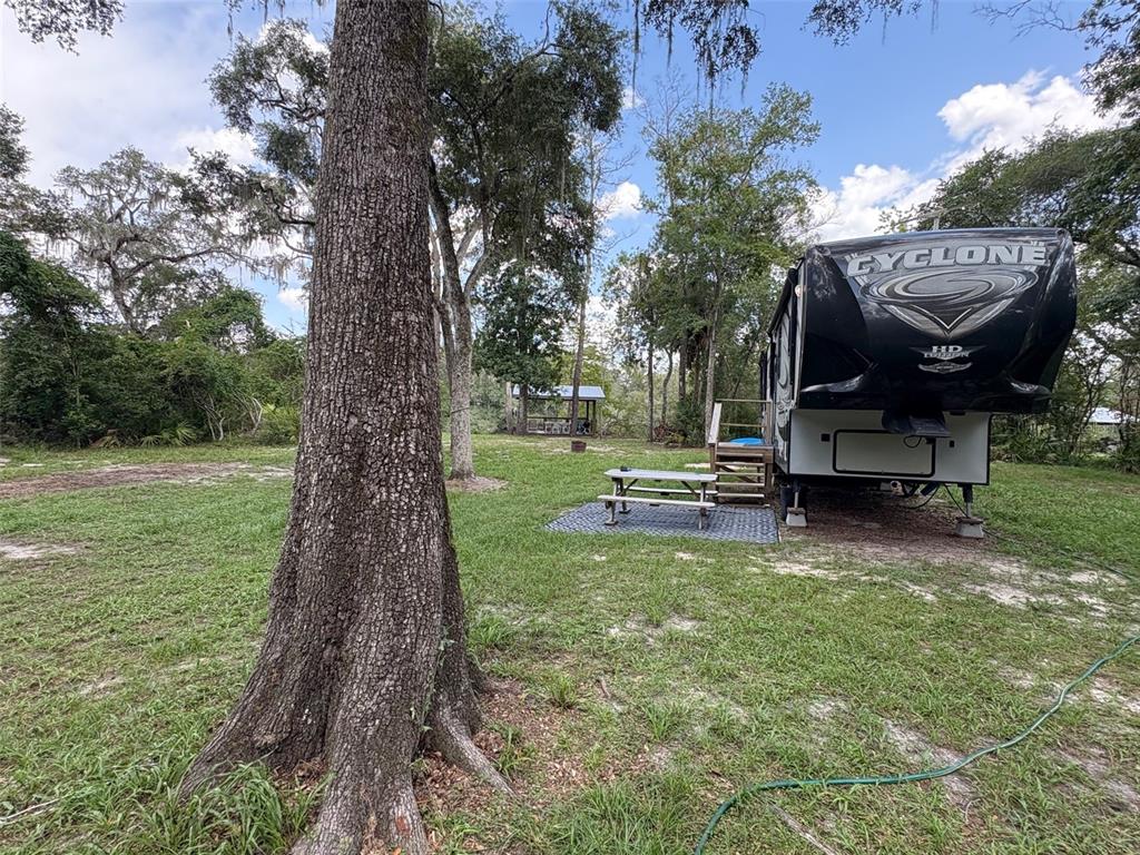 A large Cyclone fifth-wheel trailer is parked on a grassy lot with a picnic table — 1525 NE 930TH STREET, OLD TOWN, FL
