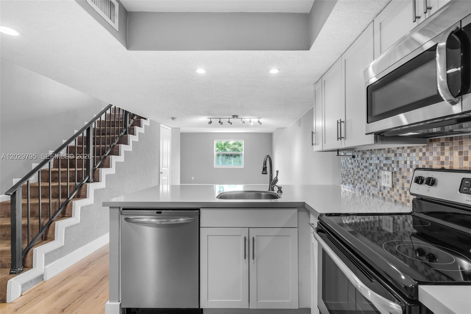 A modern kitchen features light gray cabinets, stainless steel appliances, and a staircase nearby — 4600 SW 67th Ave # 264, Miami FL 33155, MIAMI, FL