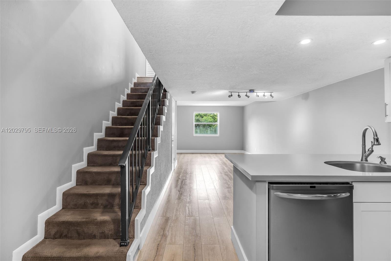 A kitchen counter and sink overlook a living area with wood floors and stairs — 4600 SW 67th Ave # 264, Miami FL 33155, MIAMI, FL