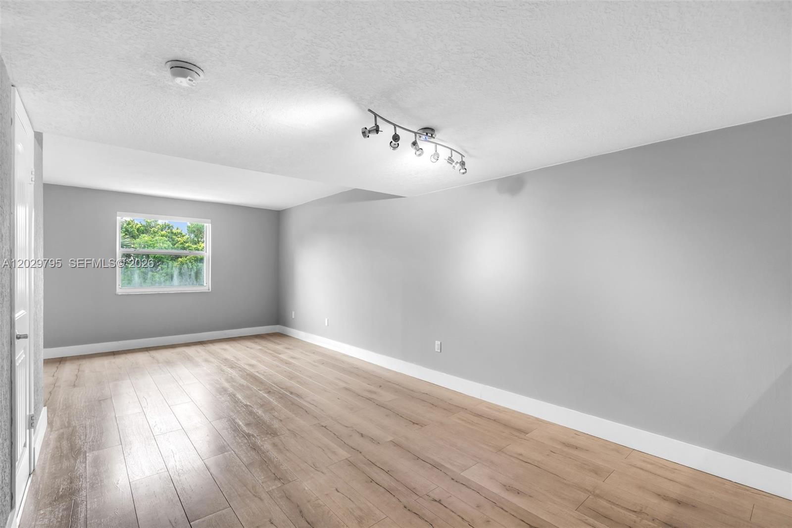 An empty room features light gray walls, wood-look flooring, and a modern track light fixture — 4600 SW 67th Ave # 264, Miami FL 33155, MIAMI, FL