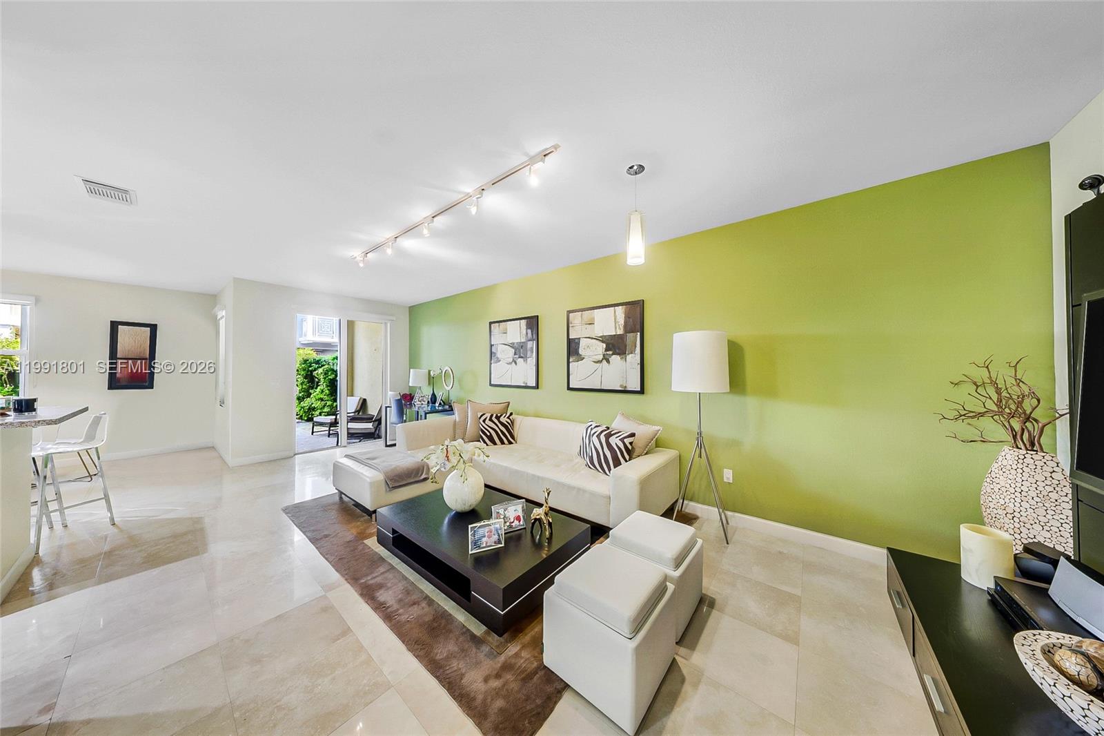 A living room features a lime green accent wall, light tile flooring, and a white sofa — 10711 NW 75th Ln, Doral FL 33178, DORAL, FL