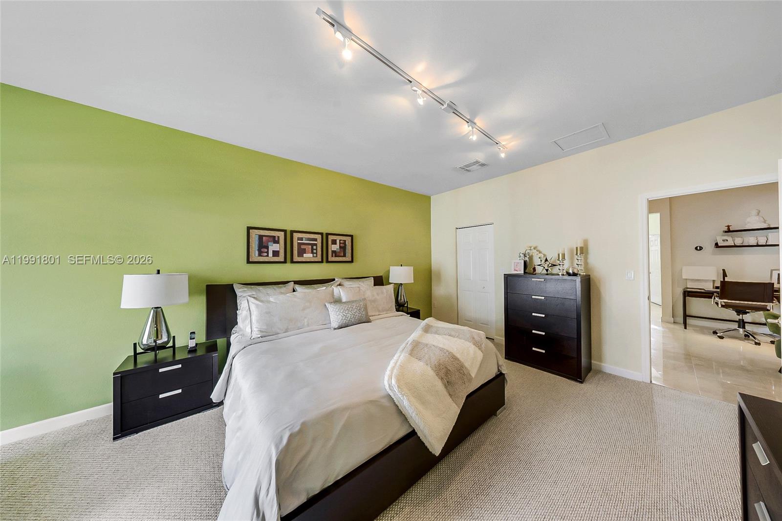 A bedroom features a lime green accent wall, dark furniture, and a track lighting fixture — 10711 NW 75th Ln, Doral FL 33178, DORAL, FL