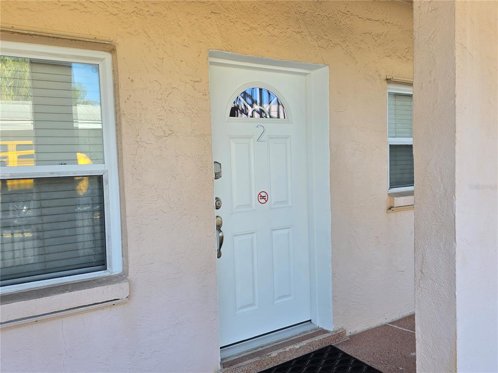 A white front door with a number two sits on a beige stucco exterior wall — 525 73RD AVENUE UNIT 2, ST PETE BEACH, FL