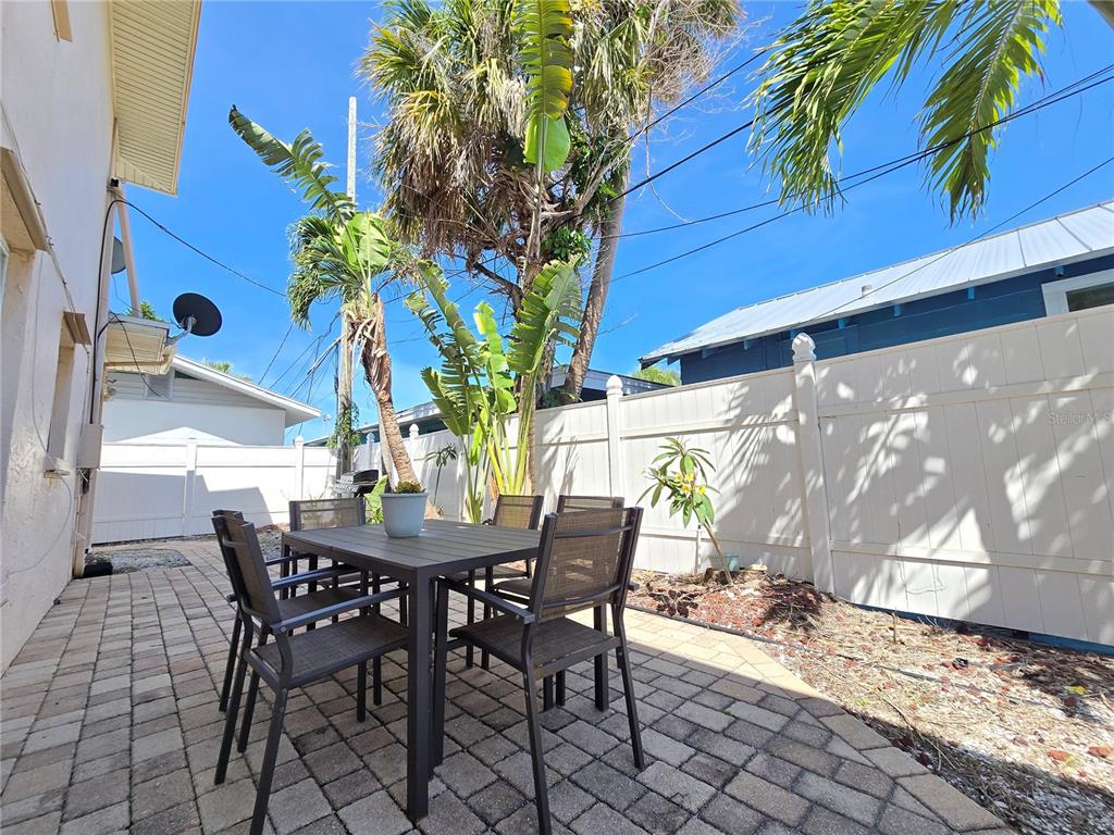 A patio with a dining set, palm trees, and a white vinyl fence — 525 73RD AVENUE UNIT 2, ST PETE BEACH, FL