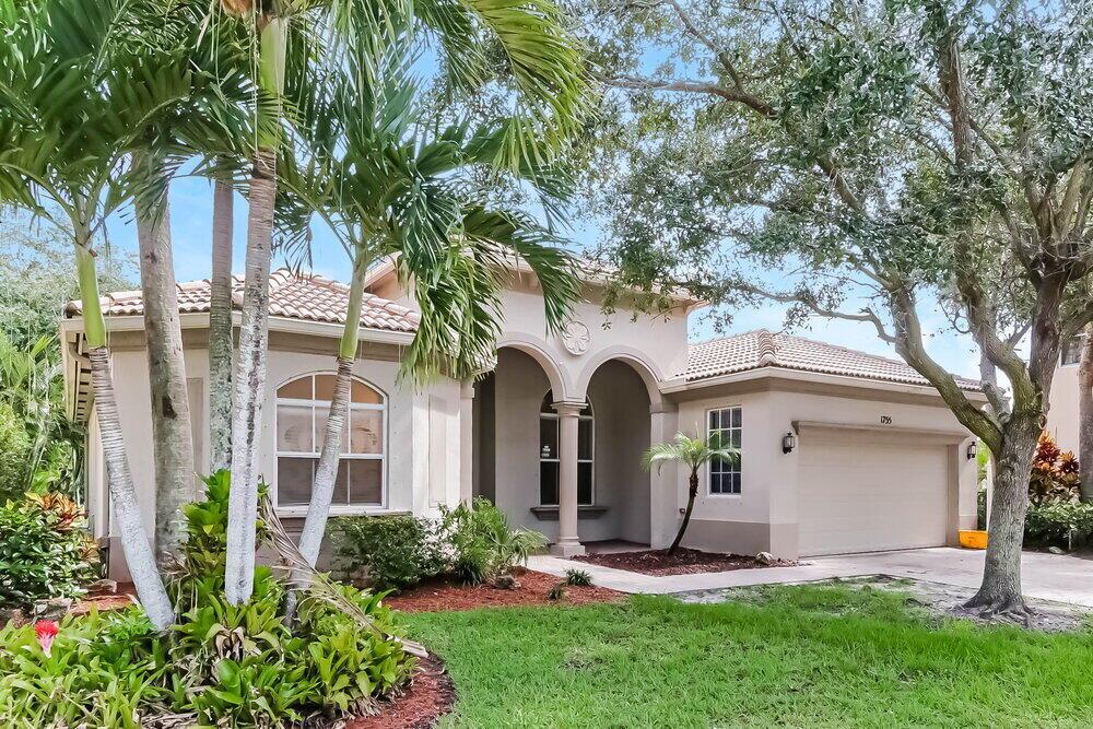 A single-story house with a beige stucco exterior, arched entryway, and a two-car garage — WEST PALM BEACH, FL