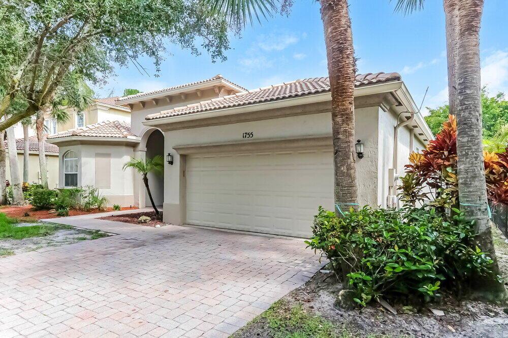 A single-story house with a beige stucco exterior, a two-car garage, and a paver driveway — WEST PALM BEACH, FL