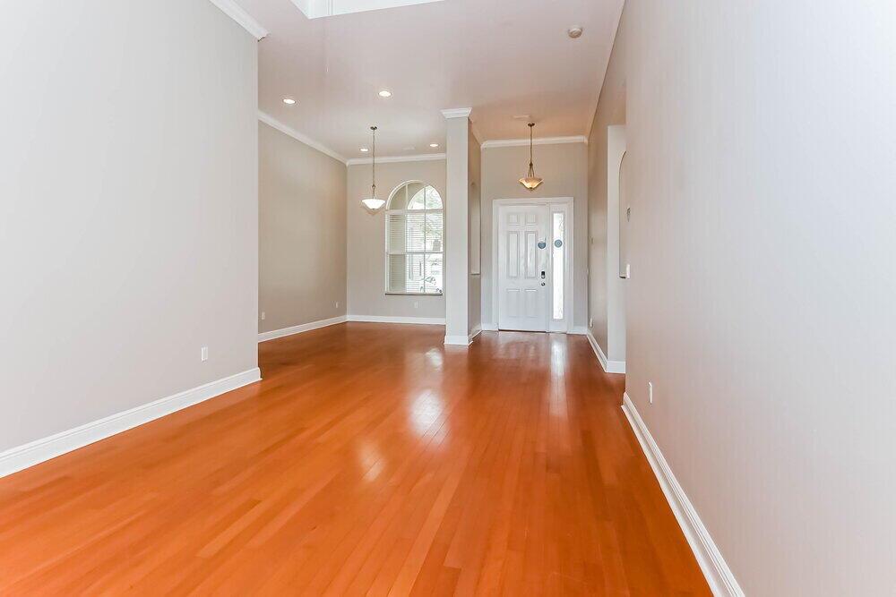 An empty room with hardwood floors, a white front door, and a large arched window — WEST PALM BEACH, FL